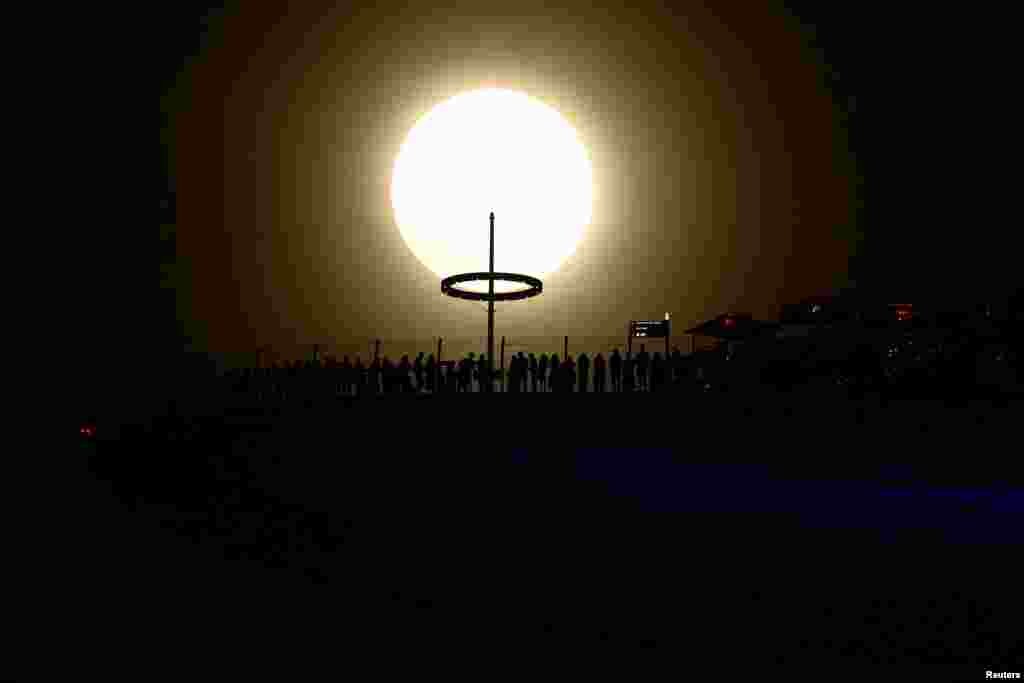 A supermoon, known as the Blue Moon, the first supermoon of the year, rises next to the Marina Bay Sands hotel in Singapore.