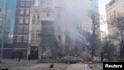Firefighters help a local woman evacuate from a residential building destroyed by a Russian drone strike, which local authorities consider to be Iranian-made unmanned aerial vehicles (UAVs) Shahed-136, in Kyiv, Oct. 17, 2022.