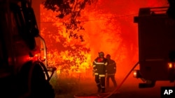 This photo provided by the fire brigade of the Gironde region (SDIS 33) shows firefighters fighting wildfire near Landiras, southwestern France, Sunday July 17, 2022 
