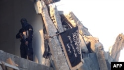 FILE - A fighter from the al-Qaida group in the Levant, Al-Nusra Front stands in a destroyed building in Yarmuk Palestinian refugee camp, south of Damascus, Sept. 22, 2014. 