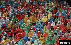 Fans yang mengenakan jas hujan dan masker wajah menonton pertandingan persahabatan pramusim Manchester United v Liverpool, di Stadion Nasional Rajamangala, Bangkok, Thailand. (Foto: Reuters)