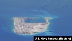 FILE - Chinese dredging vessels are purportedly seen in the waters around Fiery Cross Reef in the disputed Spratly Islands in the South China Sea in this still image from video taken by a P-8A Poseidon surveillance aircraft provided by the United States Navy.