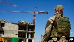 Seorang tentara Rusia tampak mengawasi pembangunan sebuah gedung apartemen baru di Mariupol, di wilayah Donetsk, Ukraina, yang kini dikuasai Rusia, pada 13 Juli 2022. Pembangunan tersebut didukung oleh Kementerian Pertahanan Rusia.(Foto: AP)