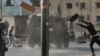 Pemuda Palestina melemparkan ban ke kendaraan tentara Israel selama operasi militer Israel di Tepi Barat, wilayah Palestina yang diduduki Israel. 