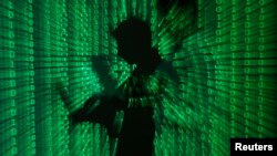 FILE - An illustration picture shows a projection of binary code on a man holding a laptop computer.