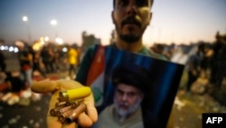 A supporter of Iraqi Shiite cleric Muqtada al-Sadr carries bullet casings and a spent shotgun shell in the capital Baghdad, Aug. 29, 2022. 