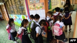 Students wearing face masks form a line as they enter their classroom during the opening of classes at a school in Quezon City, suburban Manila on Aug. 22, 2022 as millions of children in the Philippines returned to school as the academic year started.