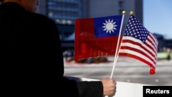 Seorang demonstran memegang bendera Taiwan dan Amerika Serikat untuk mendukung Taiwan di Burlingame, California, 14 Januari 2017. (Foto: via Reuters)