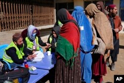 FILE - Afghans register to receive food supplies during a distribution of humanitarian aid for families in need, in Kabul, Afghanistan, Feb. 16, 2022.