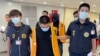 Petugas polisi dari Biro Investigasi Taiwan menggiring dua orang tersangka yang dideportasi dari Bangkok, ketika tiba di Bandara Internasional Taoyuan, Taiwan, pada 18 Agustus 2022. Keduanya diduga terlibat penipuan di Kamboja. (Taiwan Criminal Investigation Bureau via AP)