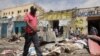 FILE - Residents look at the aftermath of an al-Shabab militant attack in Mogadishu, Aug. 21, 2022. 