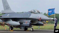 FILE - A Taiwanese Air Force flag bearer passes by an upgraded F-16V fighter jet at the air force base in Chiayi, Taiwan, Nov. 18, 2021. 
