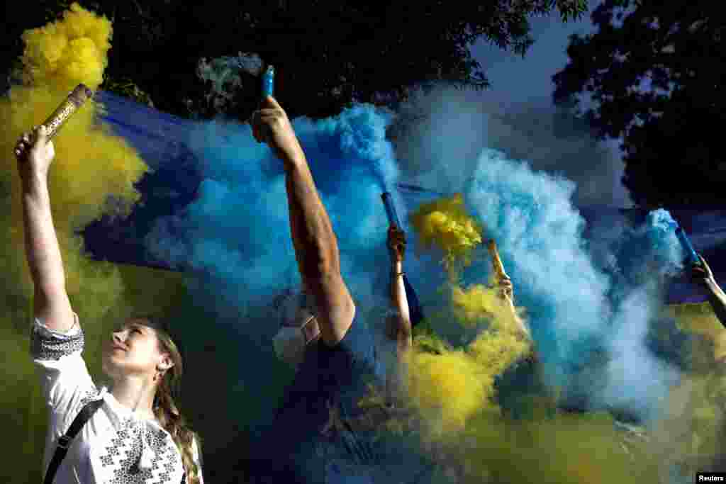 People hold flares with the colors of the Ukrainian flag as Ukrainians and supporters hold an anti-war protest outside the Russian Embassy, following Russia's invasion of Ukraine, in Mexico City, Mexico, Feb. 28, 2022.