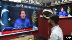 A man listens to Pakistan's Prime Minister Imran Khan addressing the nation on television at a market in Karachi, Feb. 28, 2022.