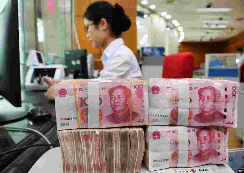 2018年7月23日在中国江苏省南通市的一家银行,一名员工处理100元纸币。随着美中两国开始打贸易战,人民币大幅度贬值。川普总统形容为“像岩石一样跌落”,并指责中国在背后操纵汇率。中国央行表示,中国“一向坚持市场化的汇率改革方向,……不搞竞争性贬值,不会将人民币汇率作为工具来应对贸易争端等外部扰动”。