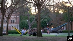 FILE - College students enjoy the outdoors at the University of Southern California campus in Los Angeles, March 1, 2022. College campuses throughout the U.S. are seeing a rise in COVID-19 cases.