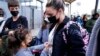A woman from Ukraine stands with her children before crossing into the United States, March 10, 2022, in Tijuana, Mexico. U.S. authorities allowed the woman and her three children to seek asylum, a reversal from a day earlier when she was denied entry.
