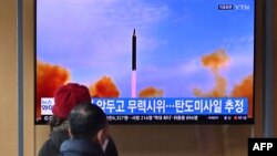 FILE - People watch a television screen showing a news broadcast with file footage of a North Korean missile test, at a railway station in Seoul, March 5, 2022.
