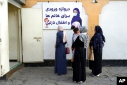 Afghan women stand outside an amusement park, in Kabul, Nov. 10, 2022. The Taliban have banned women from using gyms and parks in Afghanistan, part of their crackdown on women's rights and freedoms.