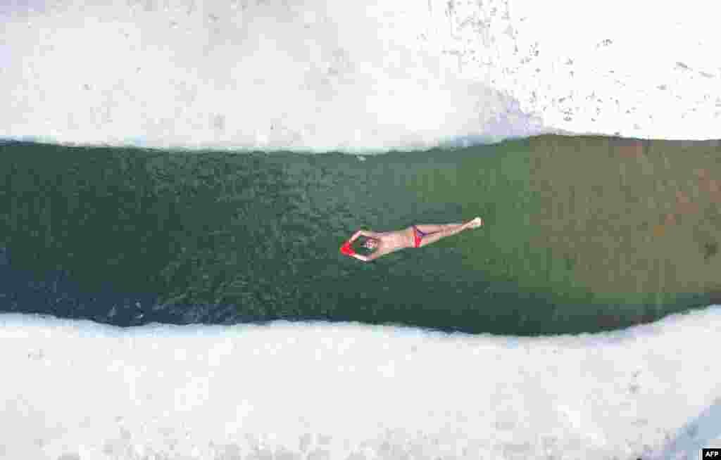 A winter swimming enthusiast floats in a partly frozen lake after snowfall in Shenyang, in northeastern China's Liaoning province.