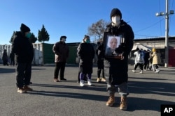 北京一家火葬場外死者親屬手捧親人的照片。（2022年12月17日）