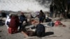 Migrants sit around a fire at a shelter on the U.S.-Mexico border in Ciudad Juarez, Mexico, Dec. 19, 2022.
