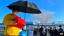 一名男子手捧親人骨灰盒走出一家北京火葬場。（2022年12月17日）