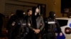 Andrew Tate dan Tristan Tate dikawal polisi di luar markas Direktorat Investigasi Kejahatan Terorganisir dan Terorisme di Bucharest (DIICOT) setelah ditahan selama 24 jam, di Bucharest, Rumania, 29 Desember 2022.
