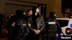 Andrew Tate dan Tristan Tate dikawal polisi di luar markas Direktorat Investigasi Kejahatan Terorganisir dan Terorisme di Bucharest (DIICOT) setelah ditahan selama 24 jam, di Bucharest, Rumania, 29 Desember 2022.