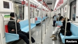 Para komuter tampak mengenakan masker ketika berada di dalam kereta bawah tanah di Shanghai di tengah perebakan COVID-19 di wilayah tersebut pada 20 Desember 2022. (Foto: Reuters/Casey Hall)