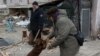 Oleksandr Sirenko, 65, looks at a woman greeting a dog as he cuts wood outside his house in the town of Siversk, Donetsk region, Ukraine, on Jan. 13, 2023, amid the Russian invasion of Ukraine.