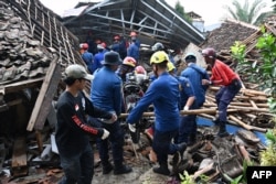 Tim SAR berupaya mengeluarkan sepeda motordari bawah reruntuhan sebuah rumah di Cugenang di Cianjur, Jawa Barat, 24 November 2022, menyusul gempa berkekuatan 5,6 pada 21 November. (ADEK BERRY/AFP)