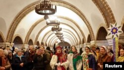 Sejumlah warga menyanyikan lagu-lagu Natal di dalam stasiun metro di Kyiv, pada 25 Desember 2022. (Foto: Reuters/Valentyn Ogirenko)