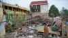 Seorang perempuan berjalan melewati reruntuhan bangunan yang rata dengan tanah akibat gempa Senin di Cianjur, Jawa Barat, Selasa, 22 November 2022. (AP/Tatan Syuflana)