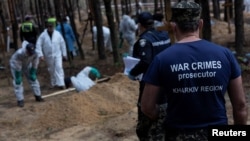 FILE - A war crimes prosecutor looks on as experts work at a forest grave site during an exhumation, as Russia's attacks on Ukraine continue, in the town of Izium, Kharkiv region, after it was liberated by Ukraine's Armed Forces, Sept. 18, 2022.