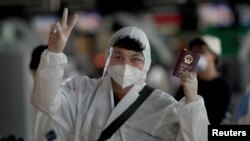 资料照：通过曼谷机场内一名身穿防护服的中国学生举起中国护照。（2020年4月21日）