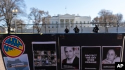 Pernyataan dan foto-foto dari orang yang terbunuh dalam invasi Rusia di Ukraina, termasuk foto jurnalis asal AS Brent Renaud, terlihat terpasang di pagar Taman Lafayette dekat Gedung Putih di Washington, dalam aksi protes menentang invasi Rusia pada 13 Maret 2022. (Foto: AP/Alex Brandon)