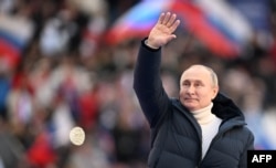 Vladimir Putin mokonzi ya Russie atamboli loboko na lisikulu lya ye liboso lya bituluku na bato na stade Luzhniki, Moscou, 18 mars 2022
