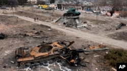 Local residents pass by a damaged Russian tank in the town of Trostyanets, east of capital Kyiv, Ukraine, March 28, 2022.
