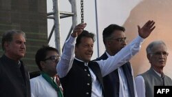Pakistan's Prime Minister Imran Khan, center, gestures upon his arrival to address the supporters of ruling Pakistan Tehreek-e-Insaf (PTI) party during a rally in Islamabad, March 27, 2022.