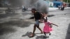FILE - A woman guides a child past a demonstration against increasing violence in Port-au-Prince, Haiti, March 29, 2022.