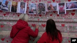 Para kerabat menulis pesan-pesan untuk orang-orang yang meninggal karena COVID-19 di monumen peringatan National Covid Memorial di London, Selasa, 29 Maret 2022. (Foto: AP Photo/Alastair Grant)
