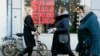 FILE - People walk past a currency exchange office screen displaying the exchange rates for the U.S. dollar and the euro to Russian rubles in Moscow, Feb. 28, 2022.