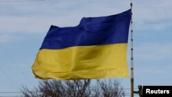 Seorang tentara Ukraina memanjat tiang bendera di pangkalan A2904 sesaat sebelum komando Ukraina kehilangan kendali atas tiang itu oleh orang-orang bersenjata di kota Bakhchisaray, Krimea, 10 Maret 2014. (Foto: Reuters)
