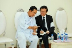 Perdana Menteri Kamboja Hun Sen, kiri, berbicara dengan oposisi utama yang dibubarkan, pemimpin Partai Penyelamat Nasional Kamboja Kem Sokha pada upacara berkabung untuk ibu mertua Sen, di Phnom Penh, Kamboja, 5 Mei 2020. (Foto: AP)