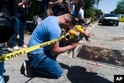 Joseph Avila, kiri, berdoa sambil memegang bunga untuk menghormati para korban yang tewas dalam penembakan di Sekolah Dasar Robb di Uvalde, Texas, 25 Mei 2022. (Foto: AP)