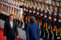 FILE - Chinese Premier Li Keqiang, left, and Solomon Islands Prime Minister Manasseh Sogavare review an honor guard during a welcome ceremony at the Great Hall of the People in Beijing, on Oct. 9, 2019.