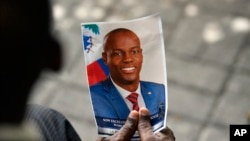Seorang warga tampak memegang foto mantan Presiden Haiti Jovenel Moise dalam upacara pemakamannya di National Pantheon Museum, Port-au-Prince, Haiti, pada 20 Juli 2021. (Foto: AP/Matias Delacroix)
