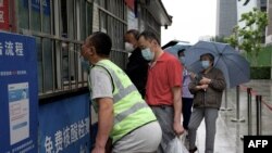 Sejumlah orang tampak mengantre untuk menjalani tes COVID-19 di sebuah lokasi tes di Beijing, China, pada 29 Mei 2022. (Foto: AFP/Noel Celis)