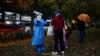 A worker in a protective suit guides people to scan health QR code at a nucleic acid test booth for the coronavirus disease (COVID-19), in Beijing, China, Nov. 11, 2022. 